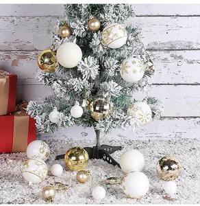 Detail of white painted and gold ornaments on a snow-covered Christmas tree branch