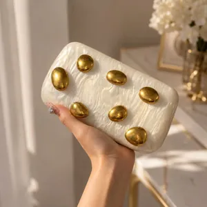 Detailed texture of white mother-of-pearl acrylic evening bag with gold pebble accents