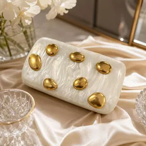 Elegant white marble acrylic clutch with gold oval accents and floral silk background