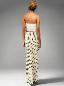 Détail du haut bandeau blanc et jupe midi cintrée à pois noirs sur tissu beige clair