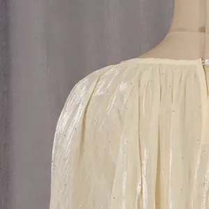 Détail de chemisier crème à manches longues en tissu plissé nacré orné de strass