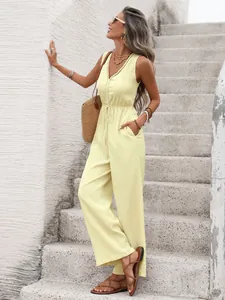 Detail of light yellow sleeveless jumpsuit featuring V-neck buttons and waist drawstring