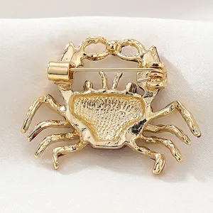 Golden enamel crab brooch with a secure rotating pin clasp on white satin background
