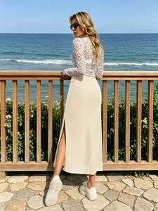 Détail d'une blouse en dentelle blanche et jupe longue beige avec fente latérale haute