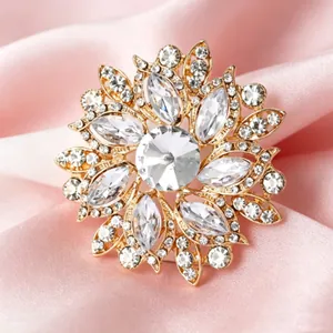 Macro d'une broche fleur dorée avec cristaux étincelants sur fond en soie rose