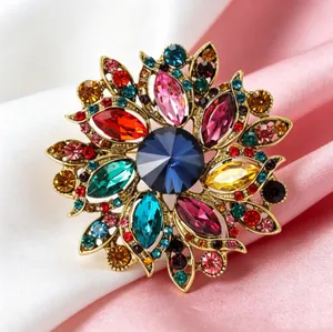 Broche florale rétro avec cristaux colorés et pierre bleue centrale sur base dorée