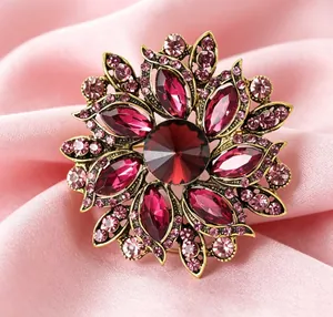 Détail macro d'une broche fleur vintage avec cristaux rouges sur soie rose luxueuse