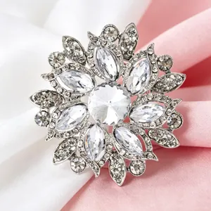 Gros plan d'une broche fleur en cristal argenté posée sur un tissu satiné rose