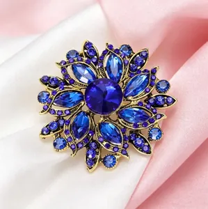 Gros plan d'une broche fleur vintage avec cristaux bleu foncé et base en métal doré