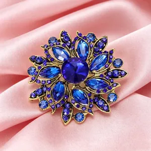 Broche florale fantaisie ornée de grands cristaux bleus sur monture en métal doré