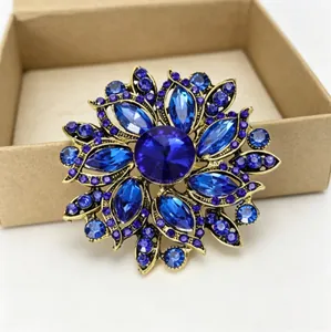 Gros plan sur une broche fleurie avec cristaux bleu roi et base dorée
