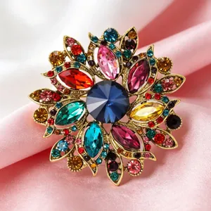Vue détaillée d'une broche fleur dorée ornée de cristaux colorés sur tissu de soie