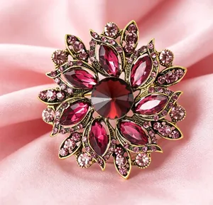Vue détaillée d'une broche florale avec gemmes rouges et cristaux sur du satin rose