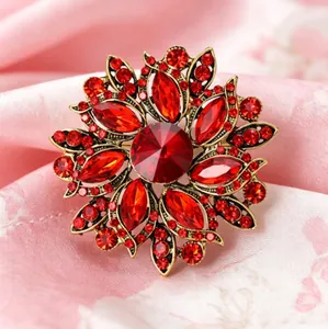 Vue détaillée d'une broche fleur vintage dorée avec cristaux rouges sur soie