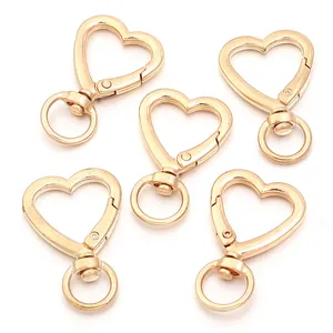 Close-up of five golden heart-shaped lobster clasps with rotating rings for DIY jewelry