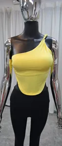 Dettaglio del top da yoga giallo monospalla con vestibilità slim e bordo inferiore curvo