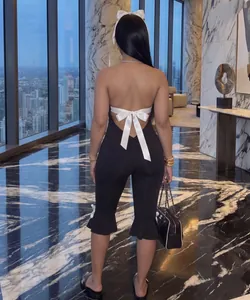 Back view of backless black romper with white satin bow detail and city view background