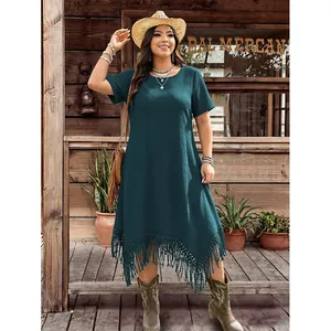 Detail of bohemian dark green dress featuring an asymmetrical hem with long tassels