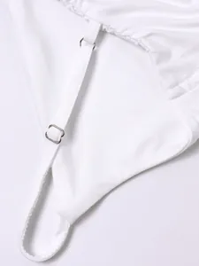 Détail d'une robe blanche en résille avec fines bretelles et boucles en métal argenté