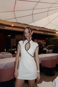 Detail of white modern cheongsam dress with black piping and teardrop cutout neckline