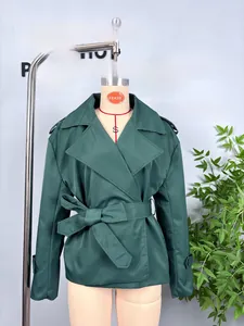 Detail of dark green cropped trench coat with classic lapels and adjustable waist belt