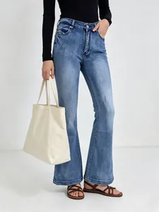 Detail of high-waisted flared jeans in washed blue denim with slim fit and flared hem