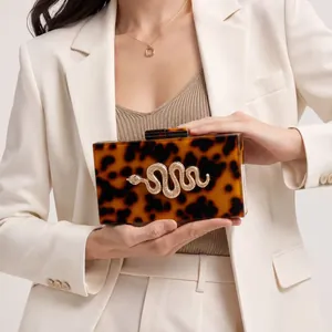Tortoiseshell acrylic clutch bag with a golden snake metal accent and chain strap