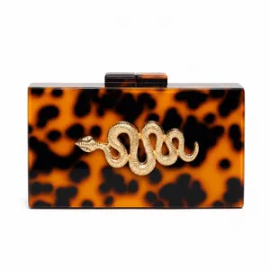 Macro detail of tortoiseshell acrylic evening bag with gold snake ornament and hard shell