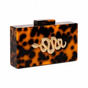 Tortoiseshell acrylic evening clutch with a gold snake emblem and box chain strap