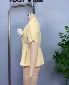 Détail du haut jaune clair à manches courtes avec décoration de fleur blanche en 3D