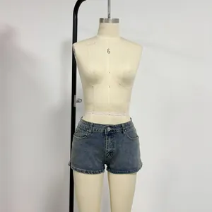 Detail of dark blue denim shorts featuring low waist and side split hem with wash effect