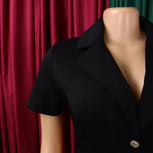 Gros plan sur un blazer noir à revers cranté avec un bouton doré élégant gravé