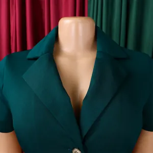 Gros plan du blazer vert foncé avec col à revers et bouton métallique élégant