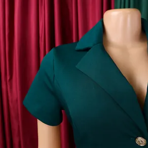 Détail du col à revers et du bouton doré sur le blazer vert foncé à manches courtes
