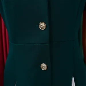 Détail du tissu d'un blazer vert foncé avec boutons dorés à motifs gravés