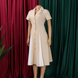 Détail d'une robe beige à manches courtes avec col tailleur et panneaux plissés blancs