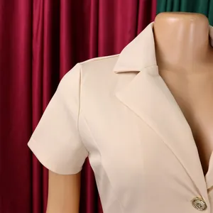 Gros plan du revers d'un blazer beige et d'un bouton doré décoratif gaufré