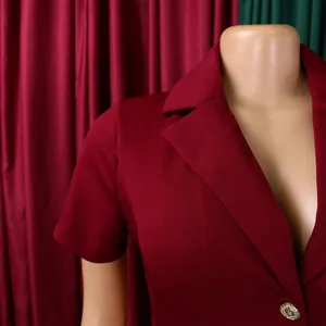 Détail d'un revers cranté bordeaux avec un bouton doré gaufré sur un blazer cintré