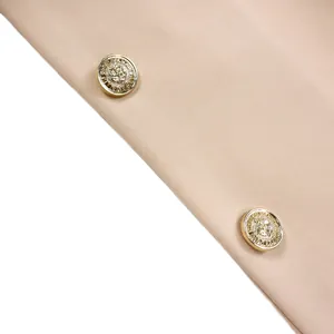 Détail du tissu blazer beige avec boutons dorés ornés d'une tête de lion et texture