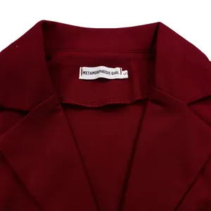 Détail du revers piqué et de l'étiquette METAMORPHOSIS GIRL sur un blazer bordeaux chic