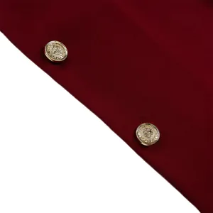 Détail macro du tissu blazer bordeaux avec boutons métalliques dorés et texture