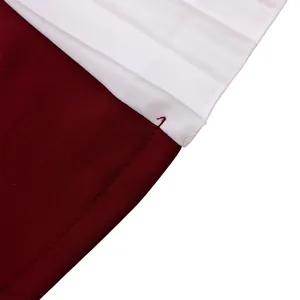 Détail du tissu rouge foncé avec panneau plissé blanc et broderie de chiffre rouge