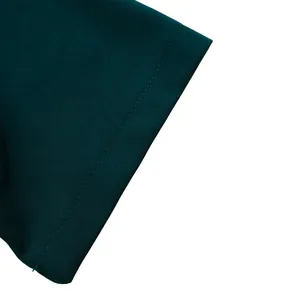 Détail des coutures nettes et de la maille fine sur l'ourlet de la robe vert foncé