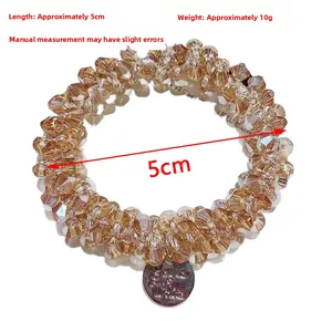 Detail of champagne gold crystal beaded elastic hair tie with engraved metal tag