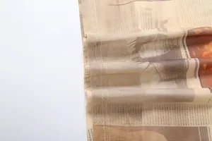 Detailed macro view of vintage newspaper print mesh fabric with double-stitched seams