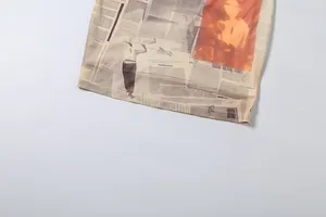 Close-up of beige dress hem featuring newspaper print and vintage red portrait detail