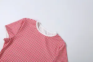 Gros plan sur le motif vichy rouge et blanc et le col rond blanc du t-shirt