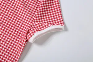 Vue macro du tissu vichy rouge et du liseré blanc sur la manchette à manches courtes