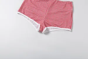 Gros plan sur le short vichy rouge et blanc avec élasticité et détails de passepoil blanc