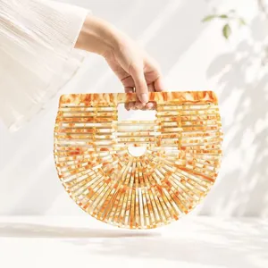 Detail of amber acrylic handbag featuring a unique hollow cut-out arc design